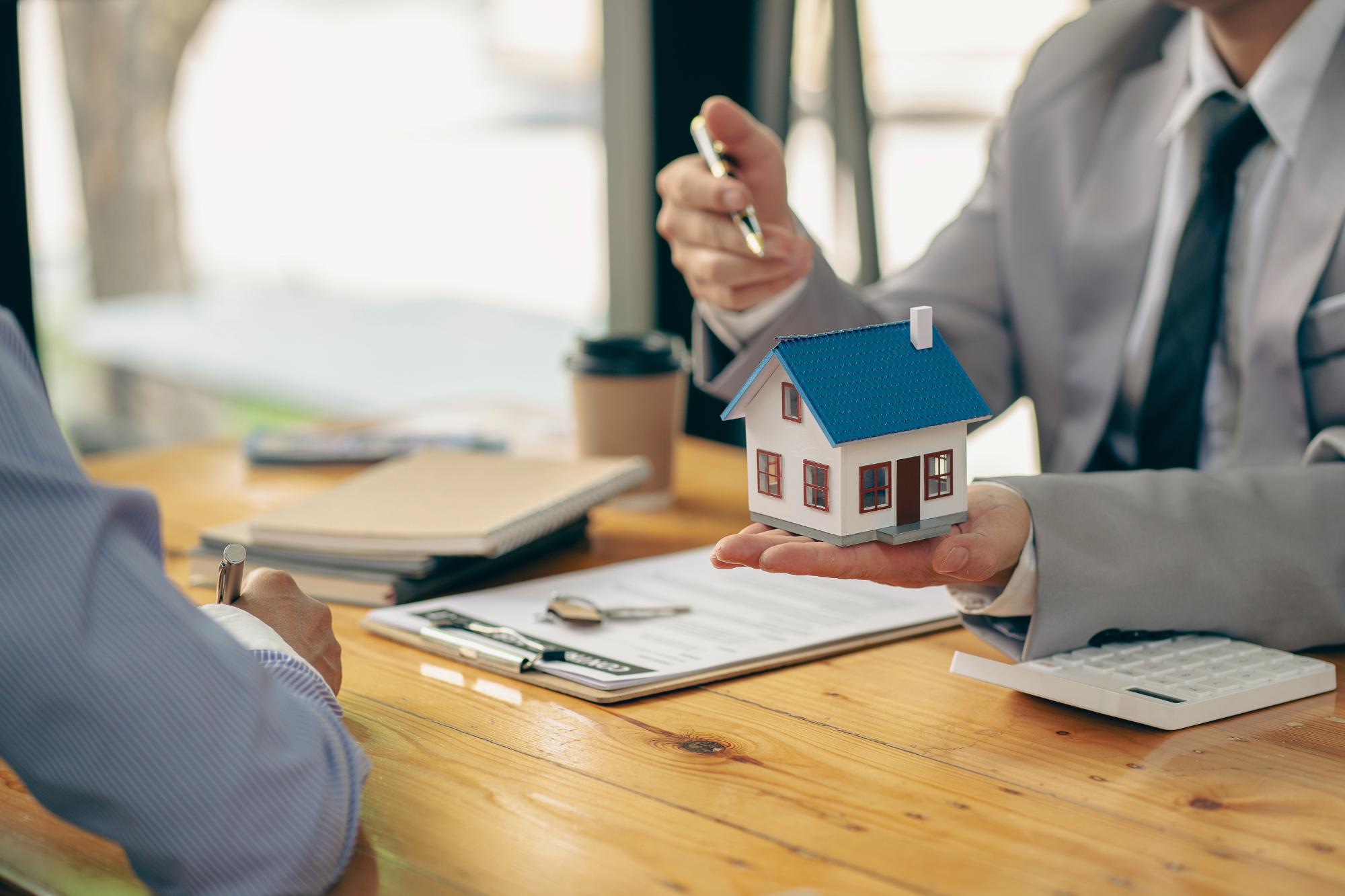 Real estate broker business Business meeting working on a new startup project. Presenting new homebuyer plan analysis ideas from sellers, home sales, renting and buying ideas. Man Holding Small House